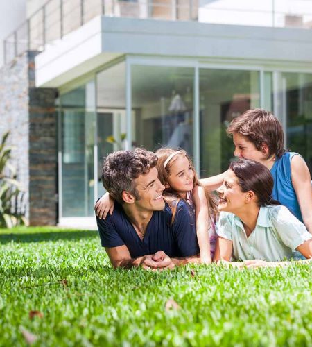 Family relaxing on the lawn outside their home, reflecting real estate and property ownership peace of mind in Fort Lauderdale