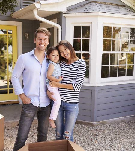 Family with young child smiling in front of their new home, representing real estate closing services in Fort Lauderdale