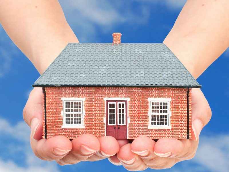 Hands cupping a miniature brick house, representing estate planning and asset protection services in Fort Lauderdale